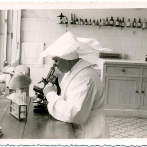 Arquivo do Reino de Galicia. Sanatorio Marítimo Nacional de Oza. Monxa a mirar por un microscopio no laboratorio do Sanatorio Marítimo de Oza (A Coruña). S.l. : s.n., 1956. Sign. 2.163.