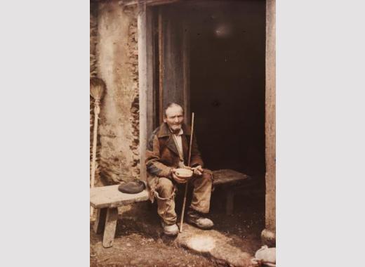 Arquivo do Reino de Galicia. Colección fotográfica. Ancián a comer nun banco na porta dunha casa. Ca. 1910-20. Sign. 6163