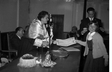 Profesora entrega un diploma a una niña, en el Instituto. J.L. Vega, 1957. Sign. 3496.2323